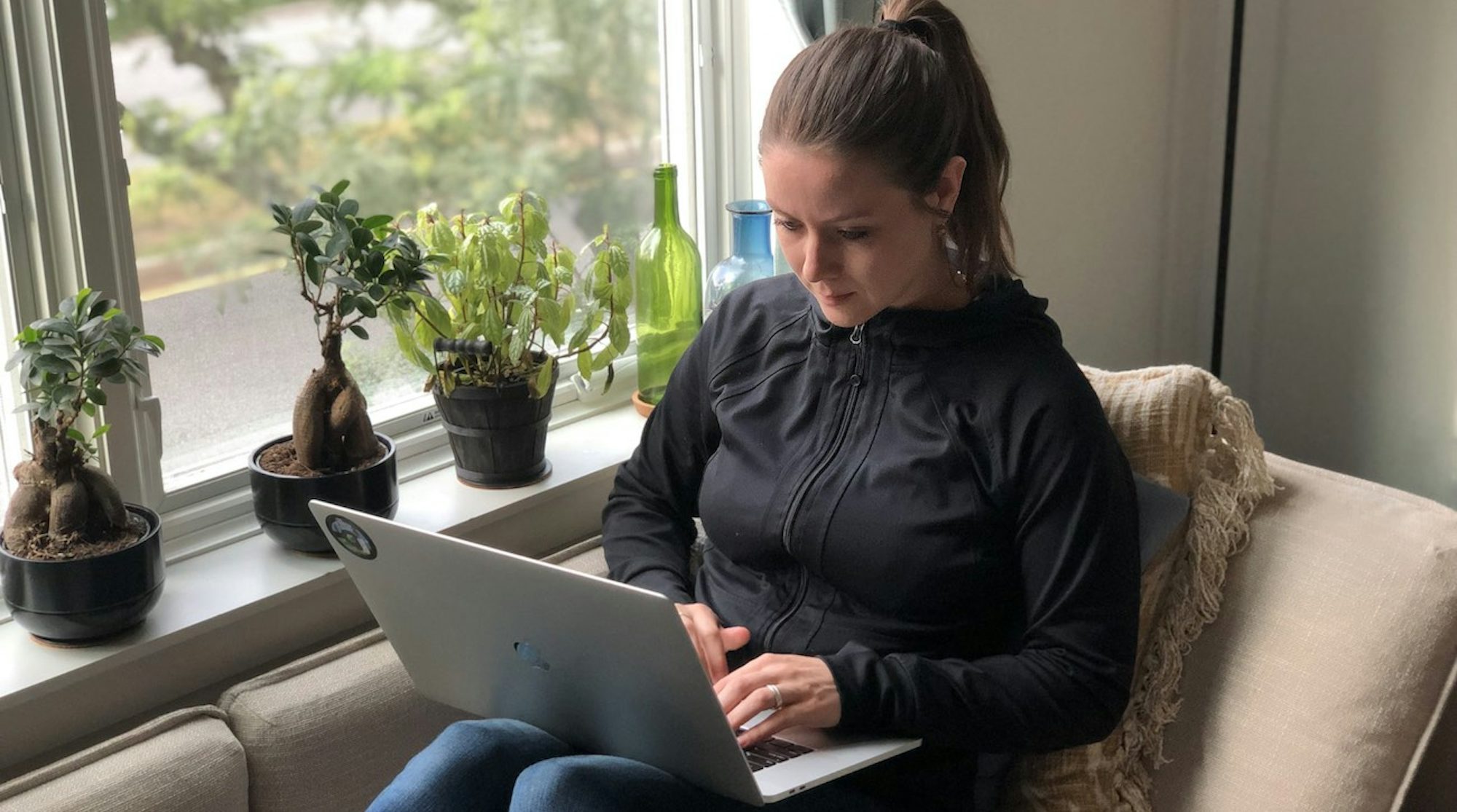 CircleCI employee working on laptop at home, seated by a window with potted plants
